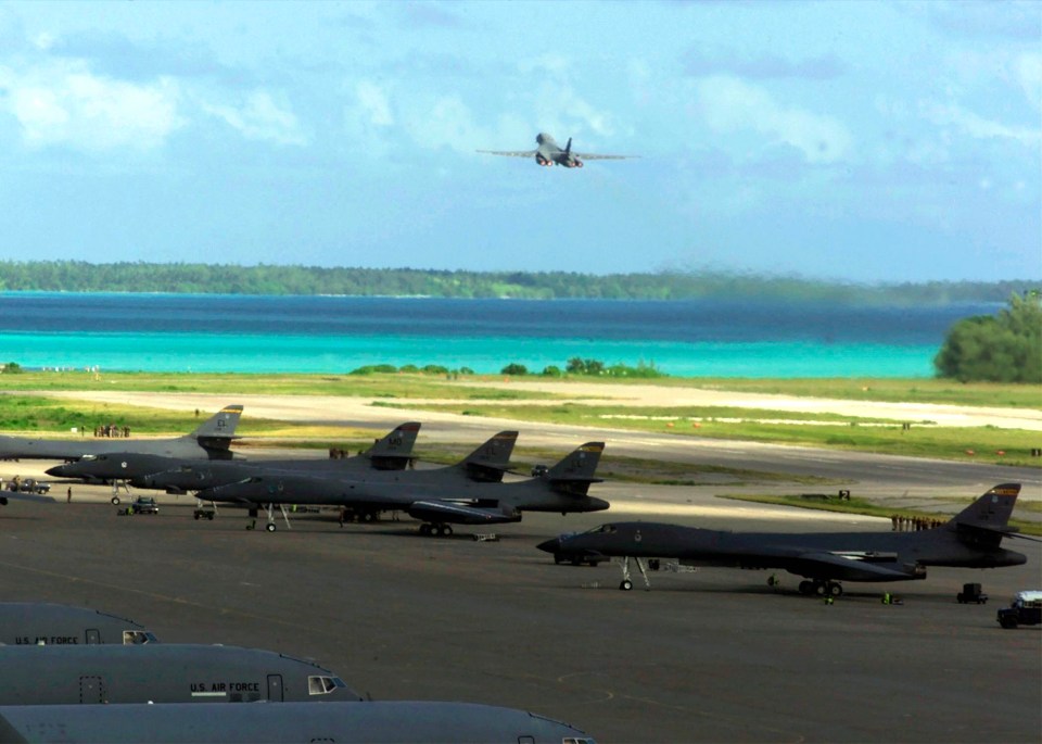 Military aircraft on a runway near a tropical island.