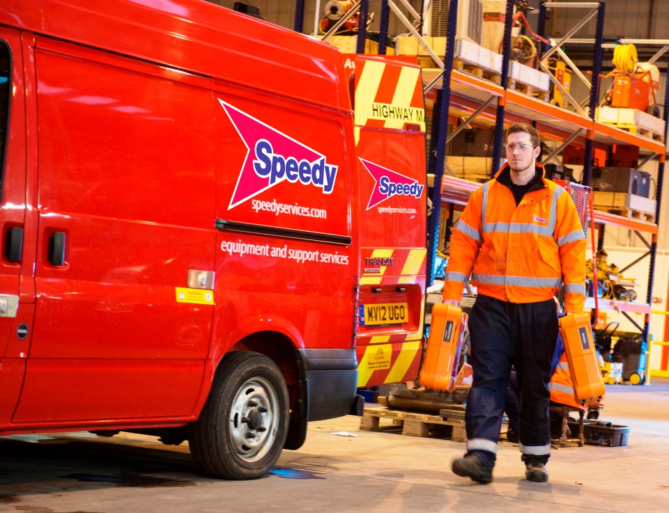 A Speedy Hire employee carrying equipment near a Speedy Hire van.