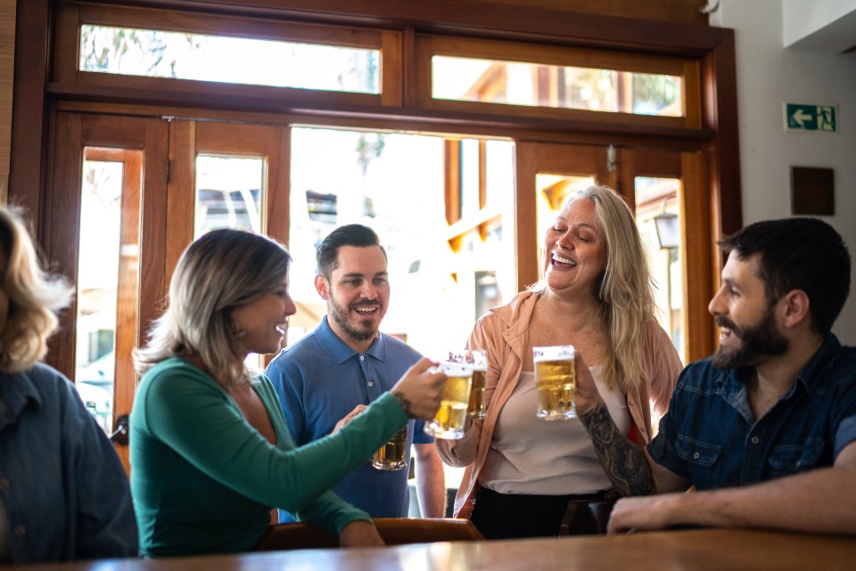 Friends toasting beer at a bar.