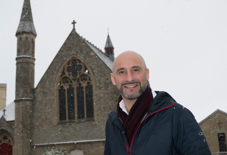 Gavin Peacock, former professional football player and preacher, smiling in the snow in front of a church.