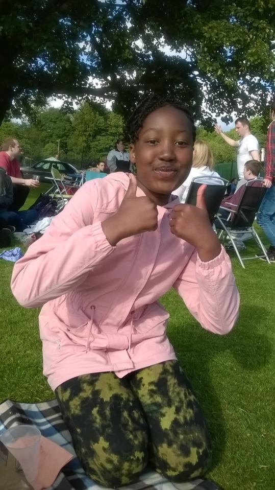 Girl giving thumbs up outdoors.