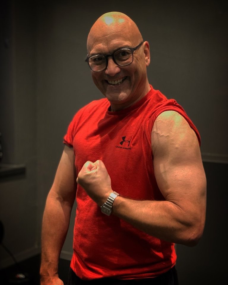 A bald man flexing his bicep.