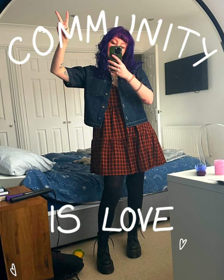 Mirror selfie of a person wearing a plaid dress and denim jacket, with text overlay that reads "Community is Love".