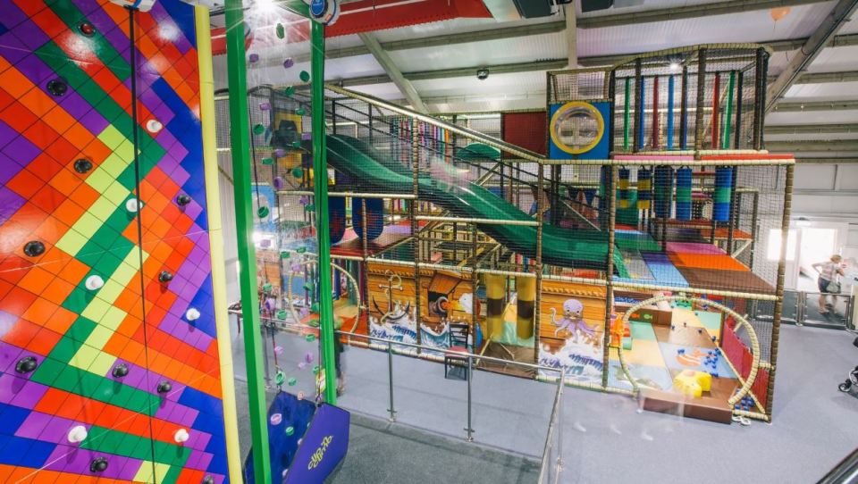 Indoor play area with climbing wall and large multi-level play structure.