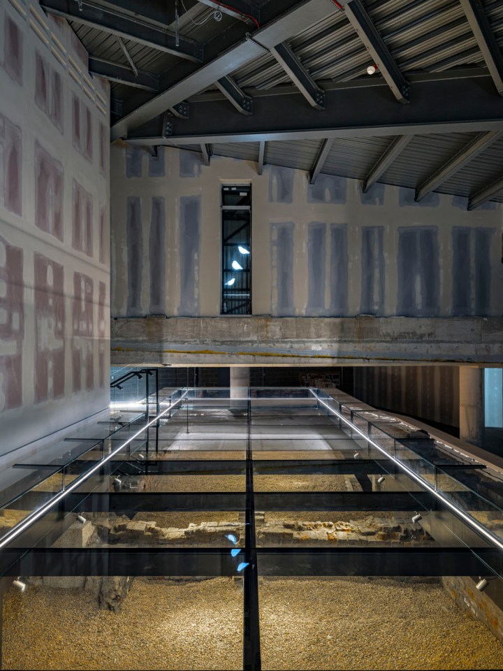 Glass floor revealing archaeological remains beneath a modern building.