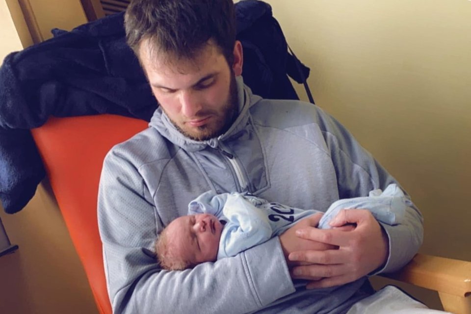 Father holding his sleeping newborn son.