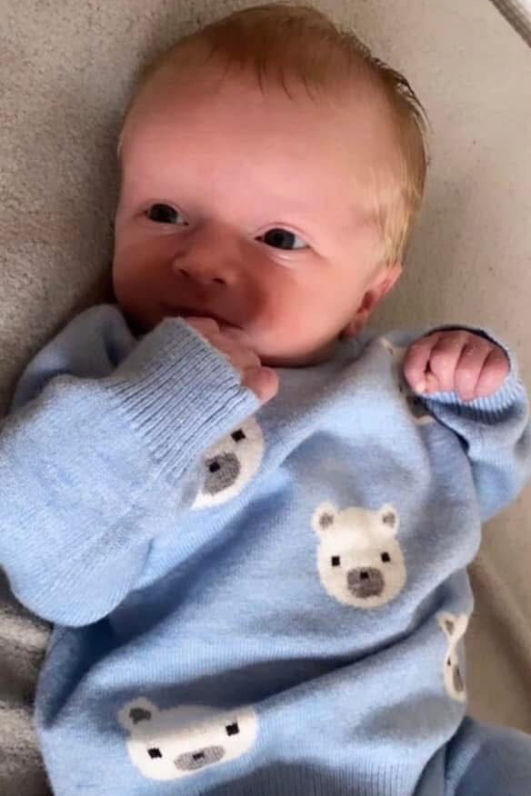 Photo of a baby wearing a light blue sweater with polar bear designs.