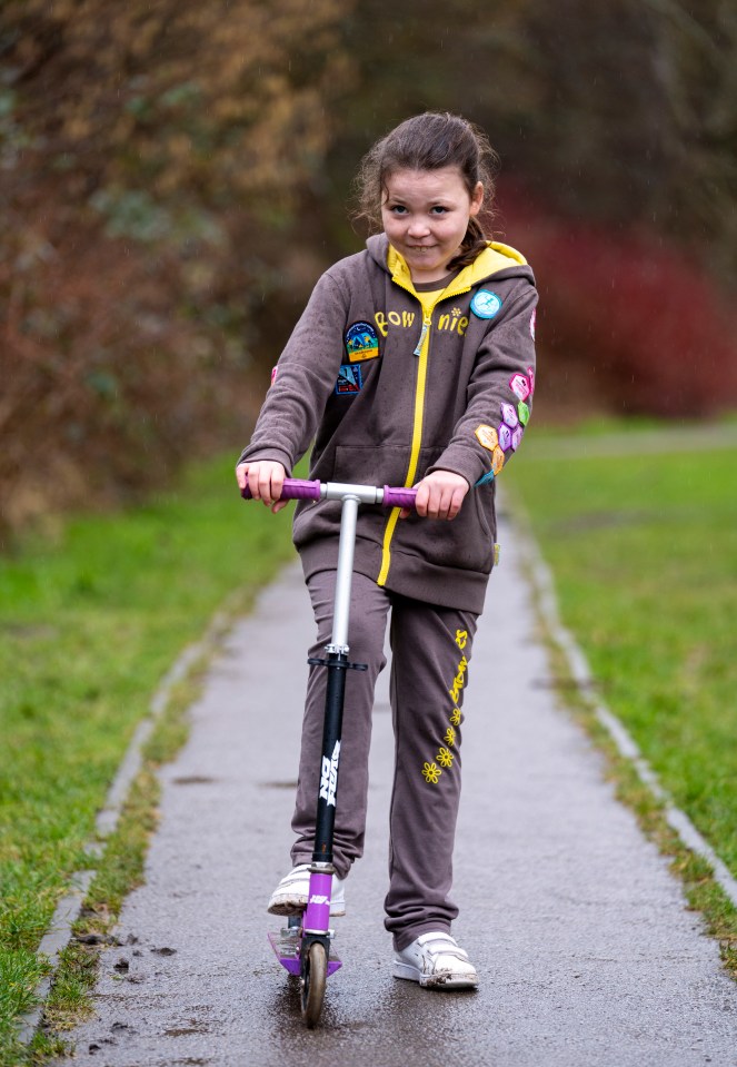 Girl Scout riding a scooter.