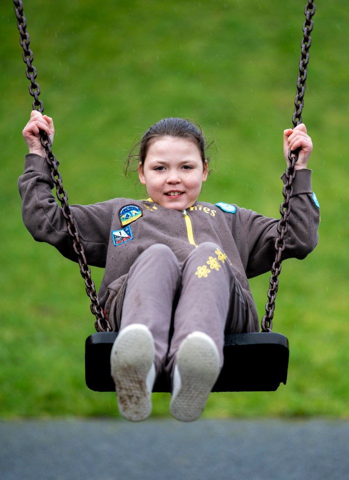 Girl in Brownie uniform on a swing.