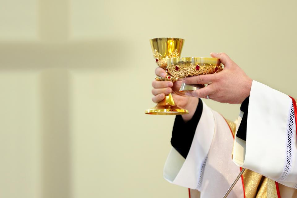 Priest holding chalice and paten during mass.