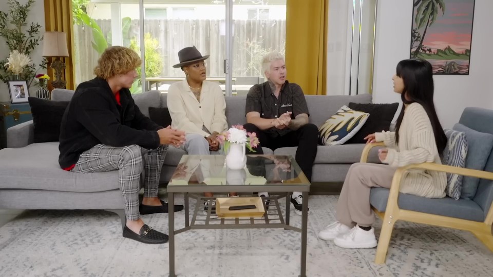 Four people sitting on a couch and in a chair, having a conversation.