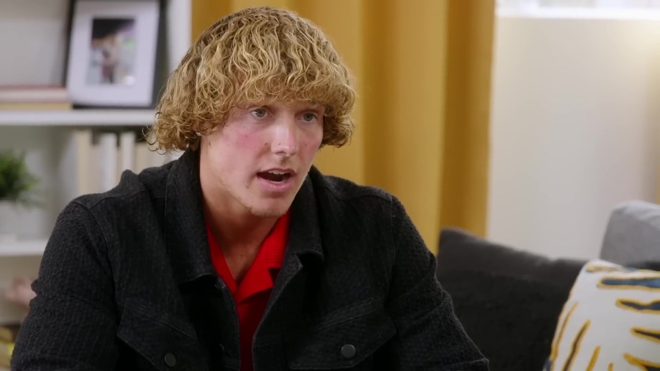 Man with blond curly hair speaks in an interview.