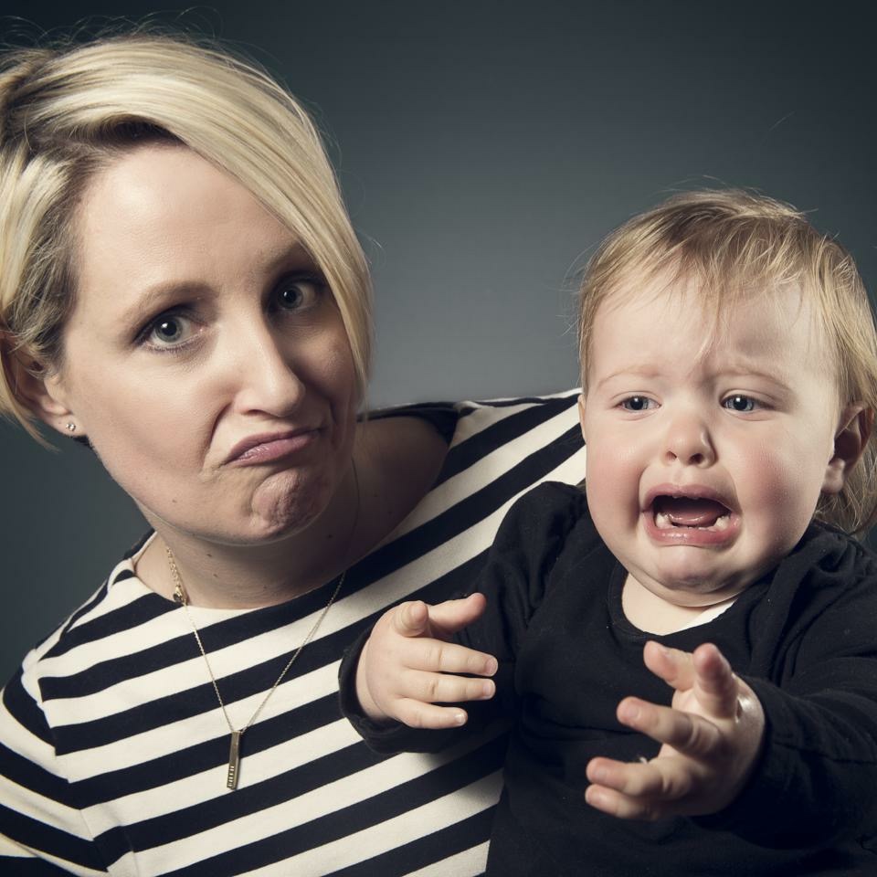 A woman holding a crying baby.