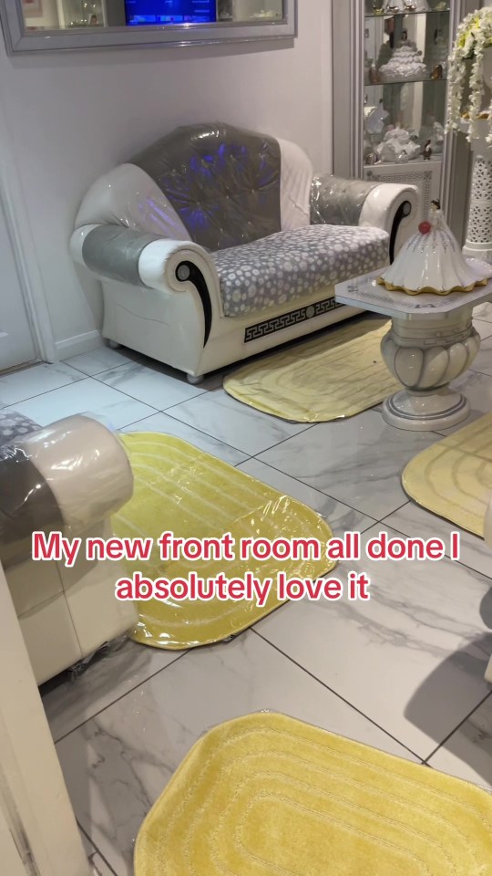 Newly decorated living room with plastic-covered furniture and yellow rugs.