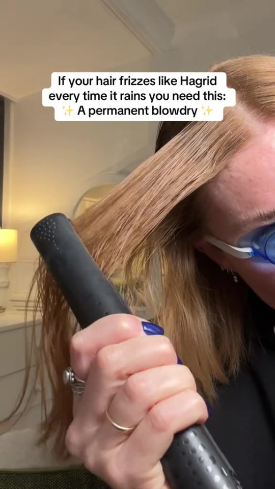 Person straightening frizzy hair with a flat iron.