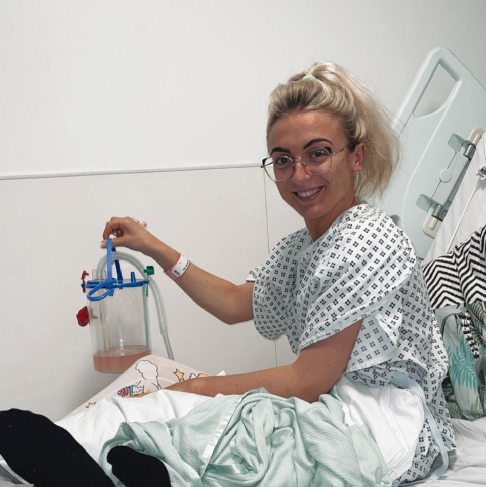 Woman in hospital gown holding a chest drain.