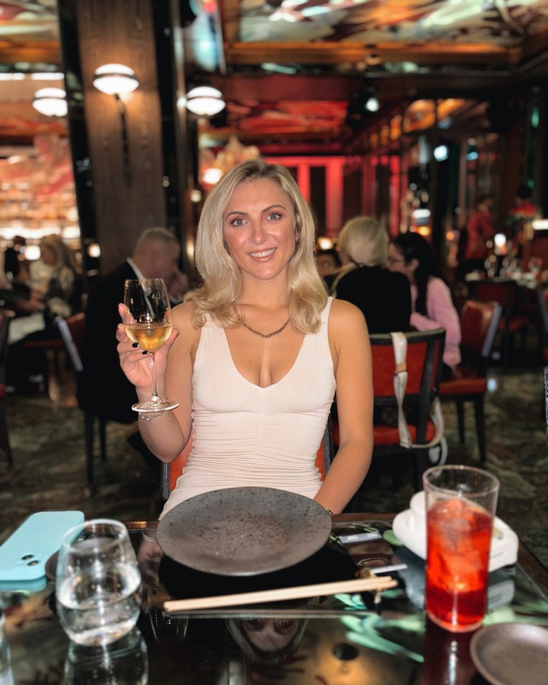 Woman holding a glass of wine at a restaurant table.