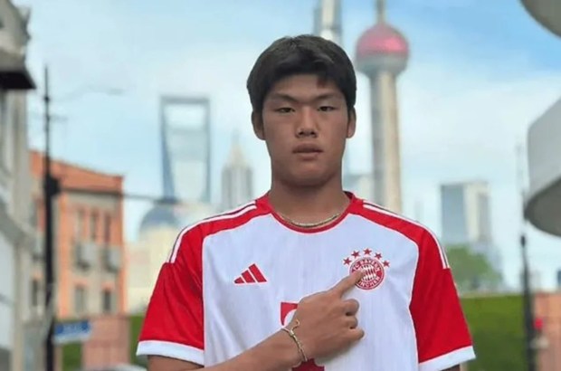 Guo Jiaxuan, a young footballer, pointing to the Bayern Munich logo on his jersey.