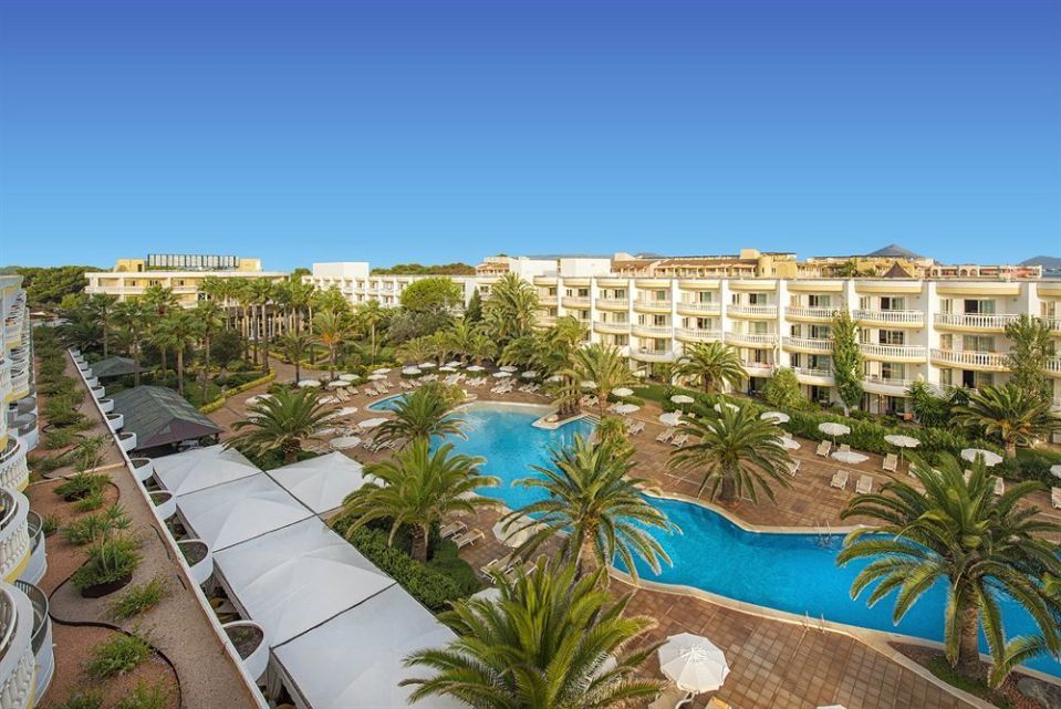 Aerial view of a resort with a large pool and surrounding buildings.