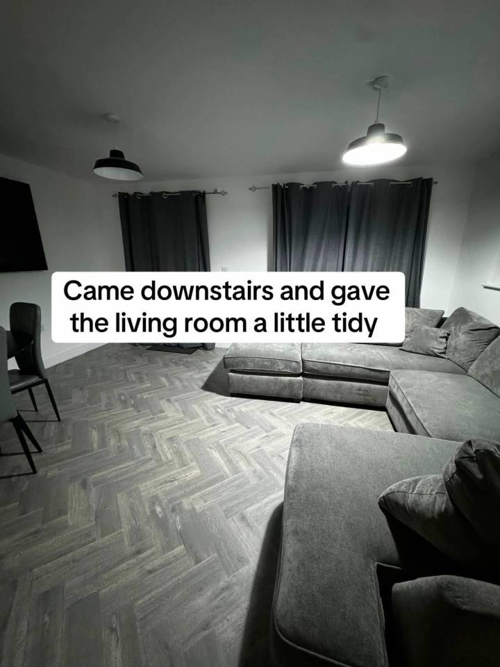 A tidy living room with gray flooring and a large gray sectional sofa.