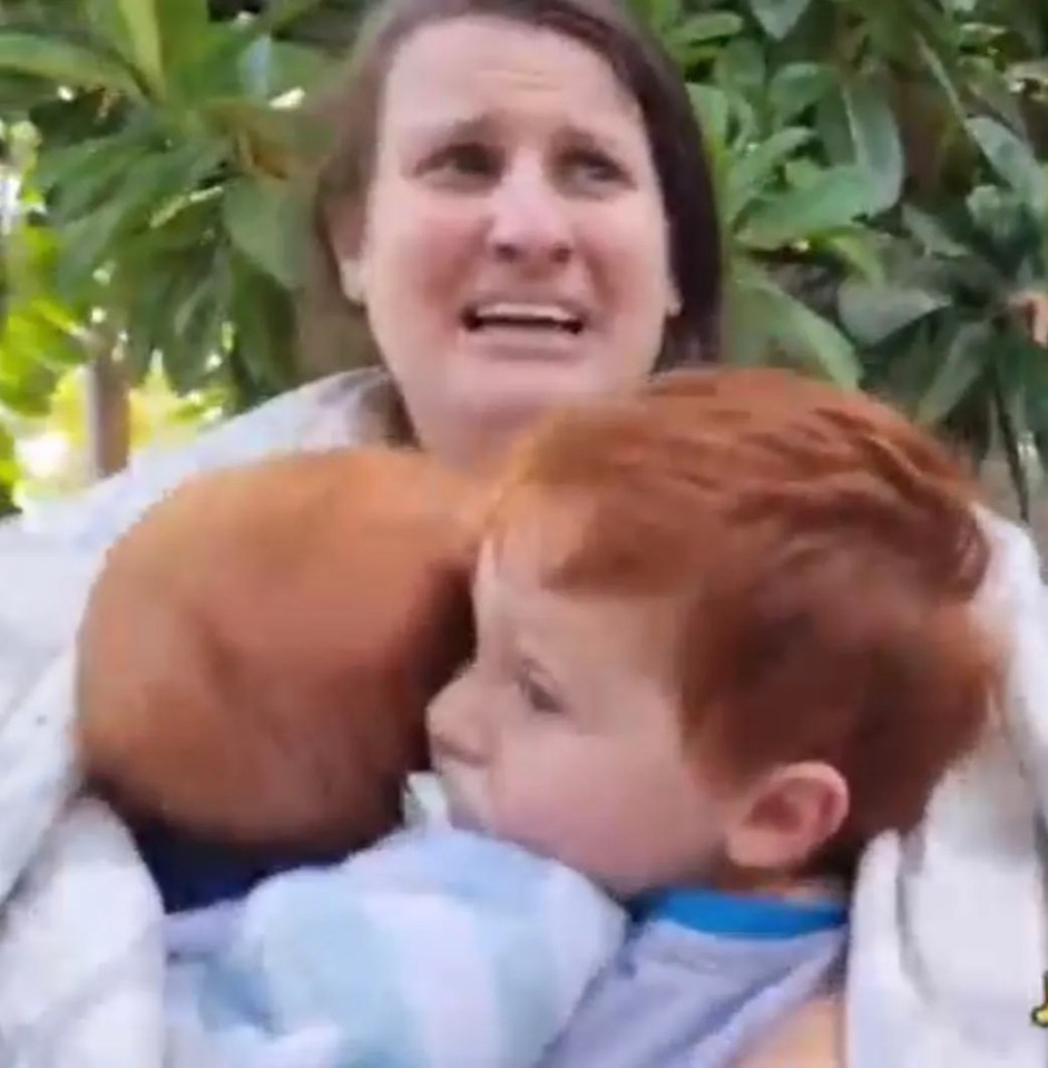 Woman holding two young children.