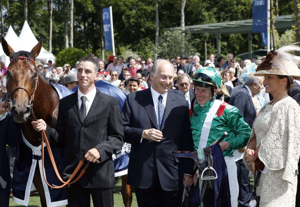 A jockey, trainer, owner, and a woman in a hat stand with a racehorse.