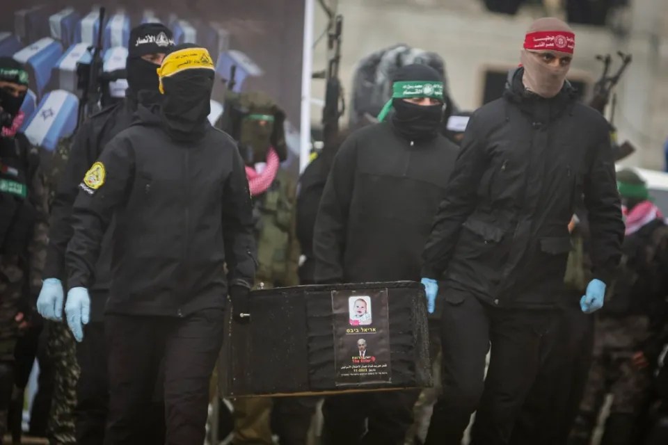 Masked men in black carrying a black box with a photo of a child.