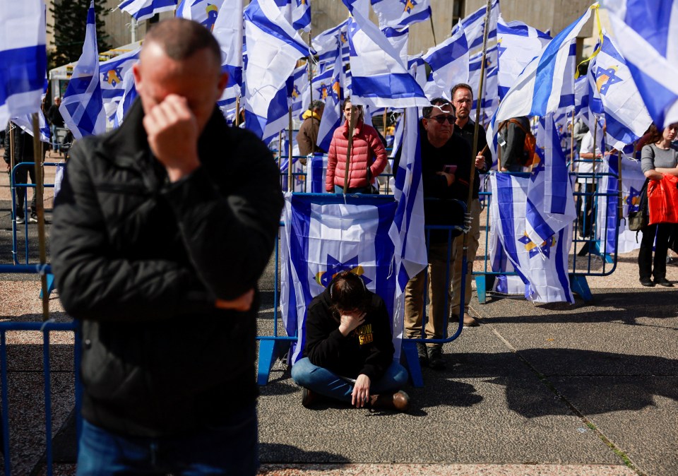 Mourners sit among Israeli flags.