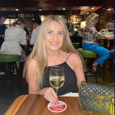 Woman at a bar holding a glass of white wine.