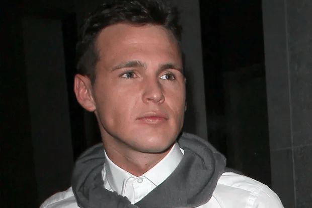 Headshot of a man wearing a white shirt and gray hoodie.