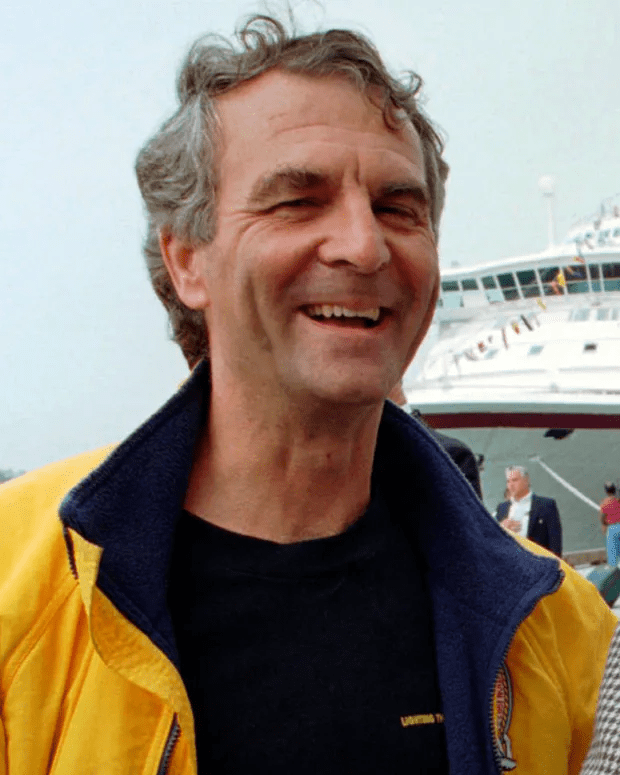 Headshot of a smiling man in a yellow jacket.