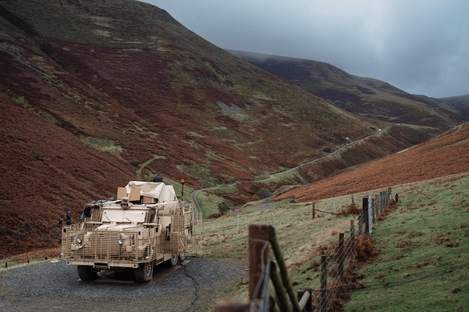 Military vehicle parked on a mountain road.