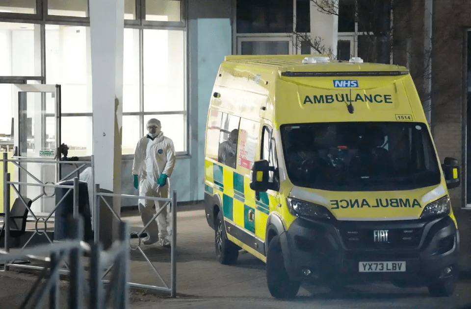 Ambulance at hospital with person in protective suit.