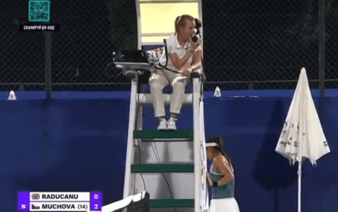 Tennis umpire on chair talking on phone, player waiting nearby.