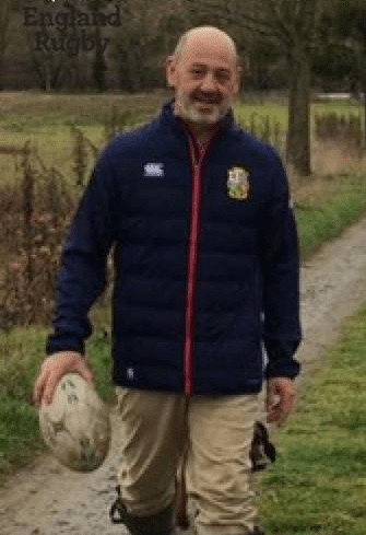 Man in England rugby jacket carrying a rugby ball.