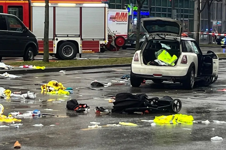 Debris and a stroller scattered on the ground near a car and firetruck.