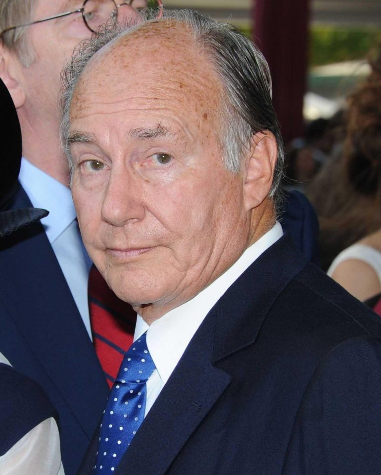 Headshot of an older man in a suit and blue tie.