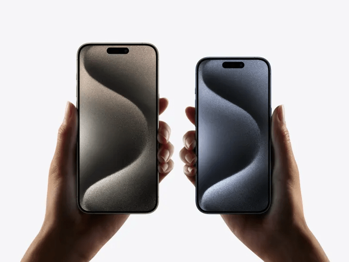 Two hands holding iPhone 15 Pro models.