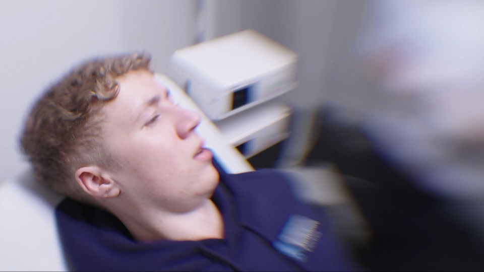 A young man lying on an examination table in a hospital.