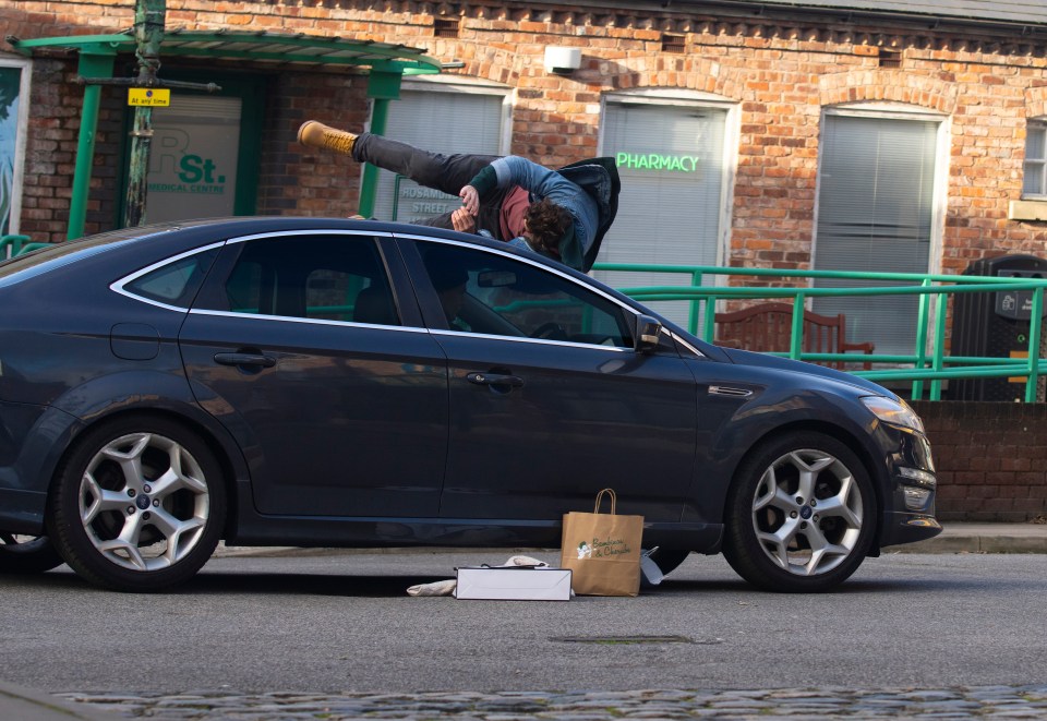 A man falling onto the hood of a car.