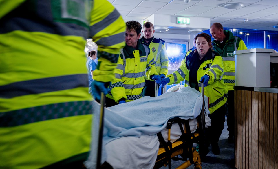 Paramedics wheeling a patient on a stretcher into a hospital.