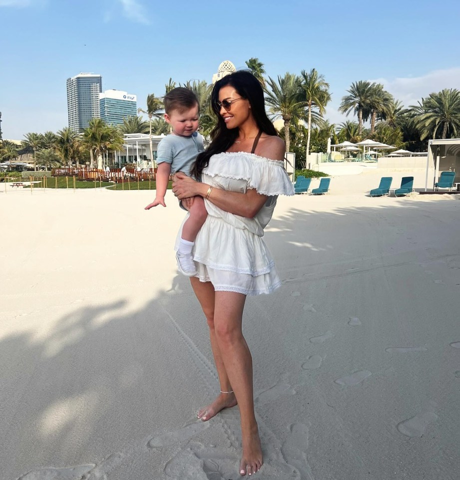 Woman holding baby on a beach.