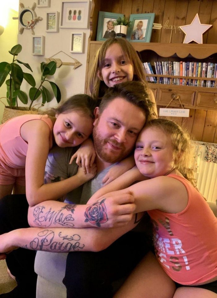 A father hugs his three daughters.