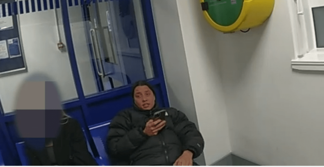 Woman looking at her phone in a police station waiting area.