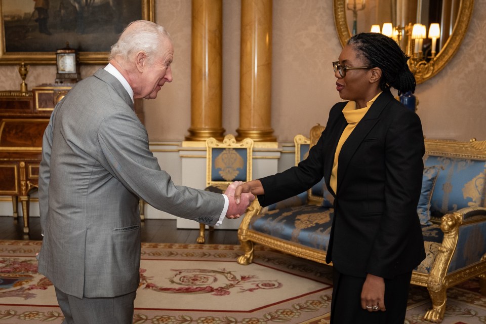 King Charles III shaking hands with Kemi Badenoch at Buckingham Palace.