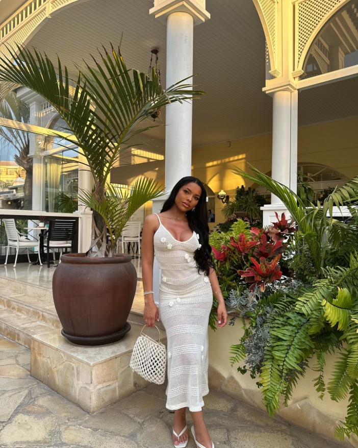 Woman in white crochet dress posing outdoors.