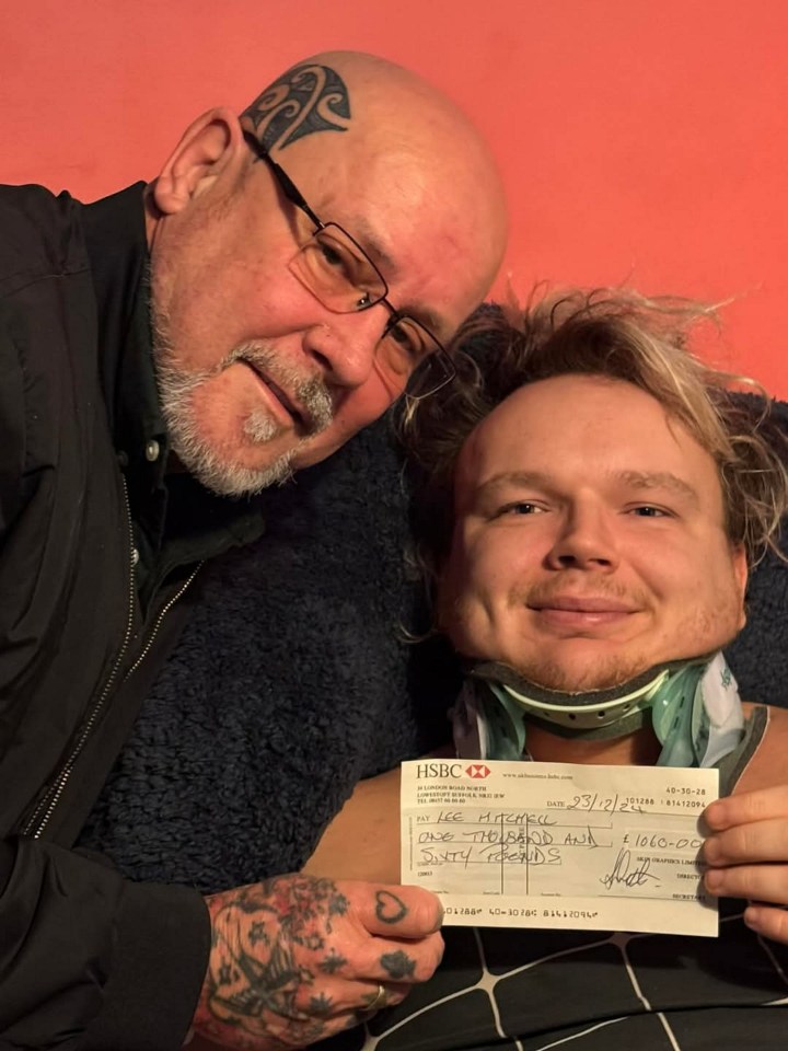 A man in a neck brace with his father holding a large check.