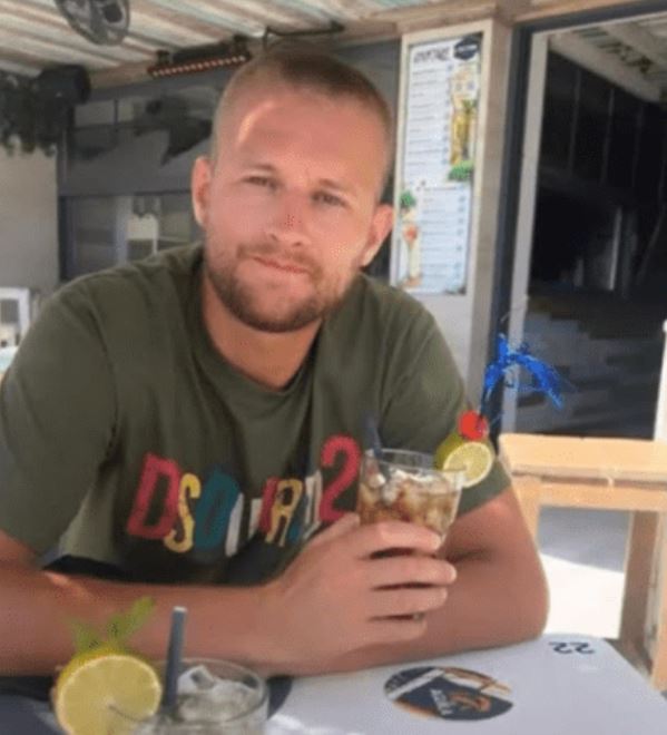 Man holding a cocktail at an outdoor cafe.