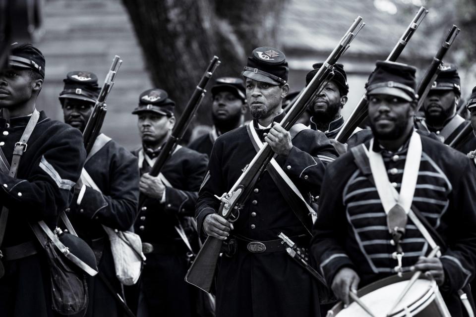 Black and white photo of a group of soldiers in uniform carrying rifles.