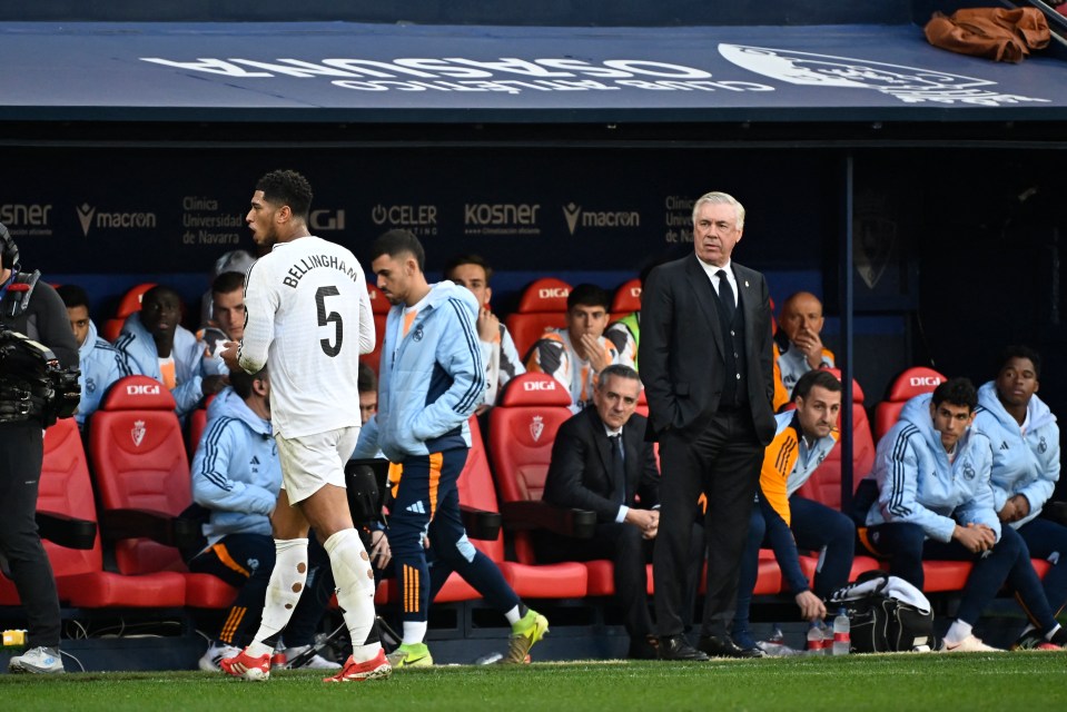 Jude Bellingham leaving the pitch after receiving a red card, with Carlo Ancelotti watching.